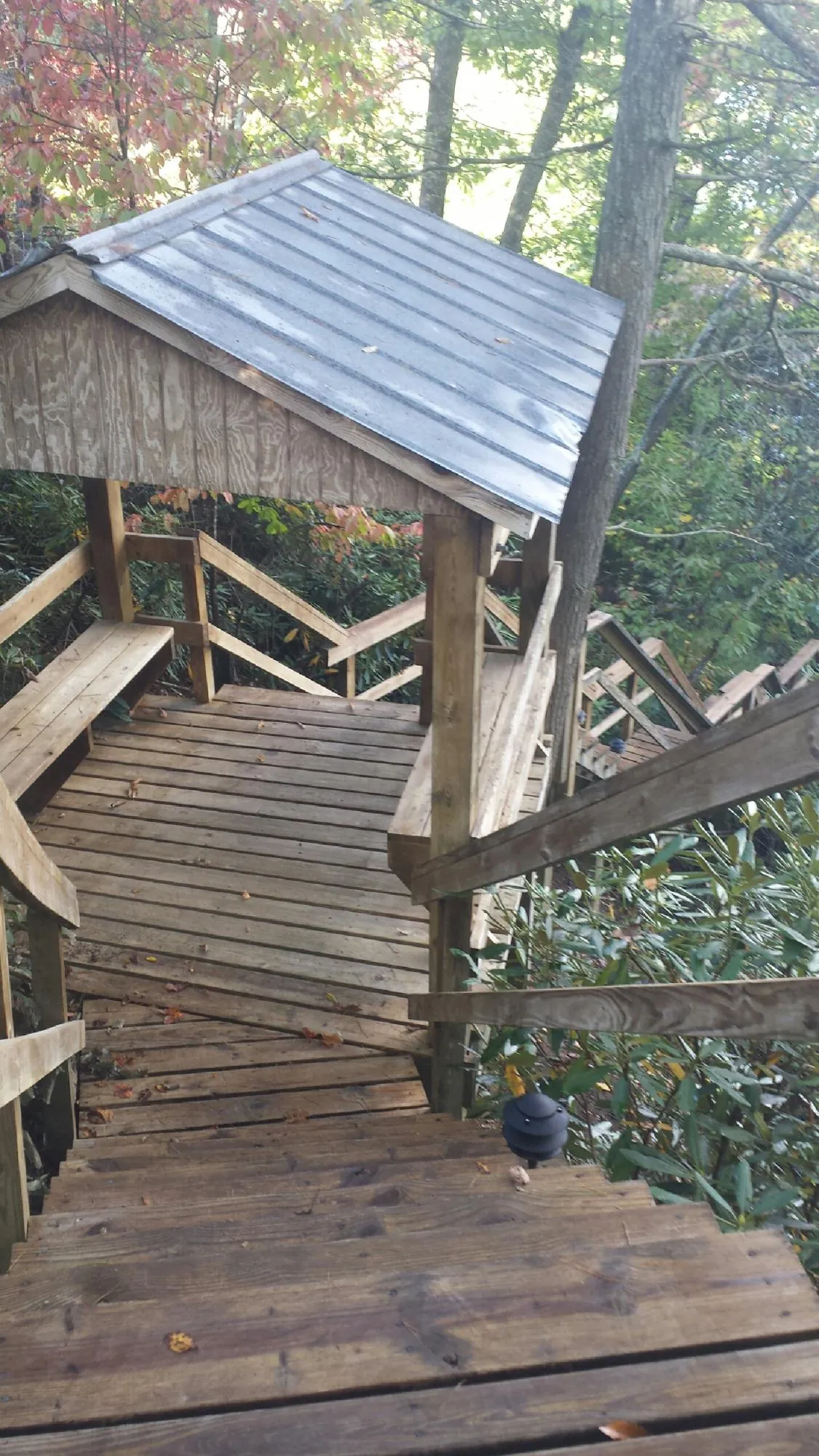 Metal roofed shelter over wooden steps on a wooded walkway — Skylight Repair & Installation work by our crew in Valparaiso
